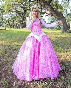 a girl in a pink princess dress posing for the camera with her arms outstretched and hands out