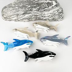 five plastic fish sitting on top of a white surface next to a rock and silver foil