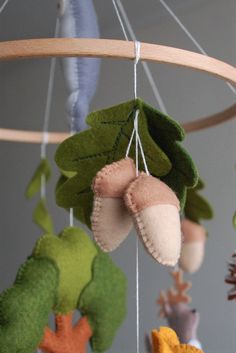 a close up of a mobile with stuffed animals hanging from it's sides and leaves attached to the strings