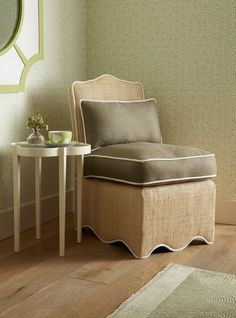 a chair sitting next to a small table on top of a hard wood floor in front of a green wall