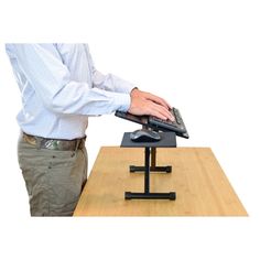 a man using a laptop computer on top of a wooden table next to a keyboard