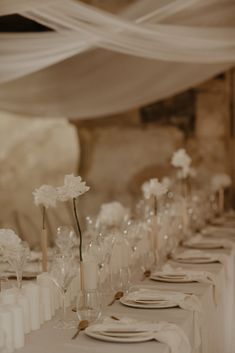 the table is set with white flowers and place settings