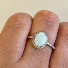 a woman's hand with a ring on it and a white opal in the middle