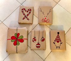 four wrapped gift boxes with christmas designs on them sitting on a tile floor next to each other