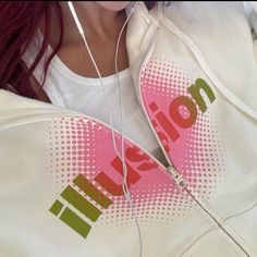 a woman with headphones on her ears wearing a white sweatshirt and pink hoodie