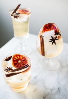 two glasses filled with drinks sitting on top of a marble counter next to each other