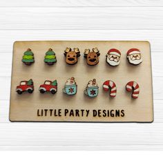 a wooden sign with christmas decorations and santa clause faces on it's sides, along with the words little party designs