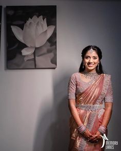 a woman standing next to a white flower in front of a painting on the wall