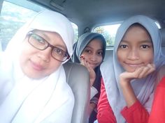 three women sitting in the back of a car with their heads wrapped around each other