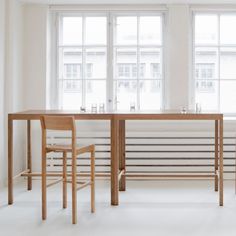 two wooden chairs sitting at a table in front of large windows with barstools