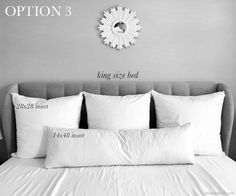 a bed with white pillows on top of it and a clock above the headboard