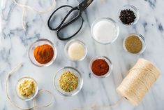 various spices and scissors on a white marble counter top with twine, spools of thread, and other items