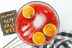 a drink with orange slices and spider legs on it, next to a happy halloween sign