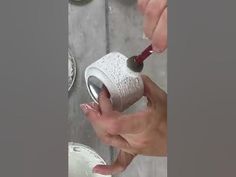 someone is holding a white cup with something red in it while they are painting the walls