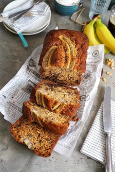 sliced loaf of banana bread sitting on top of a paper towel next to some bananas