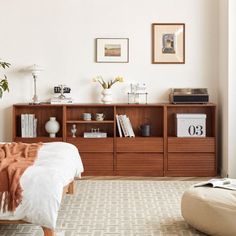 a bed sitting next to a wooden book shelf filled with books on top of a hard wood floor