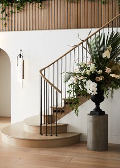 a vase filled with flowers sitting on top of a wooden floor next to a stair case