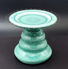 a green vase sitting on top of a black table