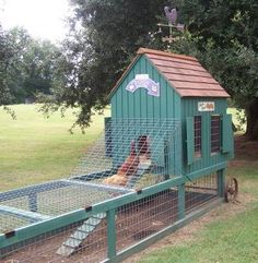 a green chicken coop with two chickens in it's cage and a dog inside