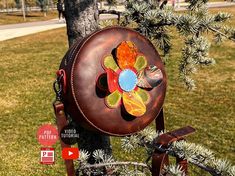 a metal flower decoration hanging from a tree in a park with grass and street signs