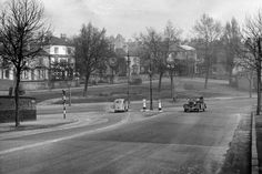 an old black and white photo of cars driving down the road