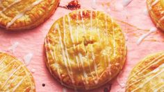 several pastries with icing sitting on top of a pink paper covered in white glaze