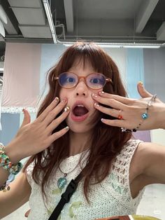 a woman with her hands on her face and wearing glasses, posing for the camera