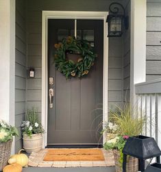 the front door is decorated with wreaths and potted plants