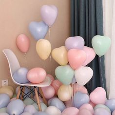 a room filled with lots of balloons floating in the air next to a white chair