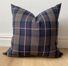 a blue and green plaid pillow sitting on top of a wooden floor next to a white wall