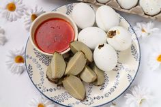 an egg shell and some kind of sauce on a blue and white plate with daisies