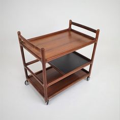 a wooden serving cart with two black trays on each side and one open shelf