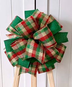 a green and red plaid bow on top of a wooden tripod with clothes pins