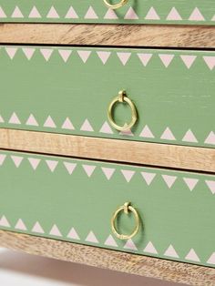 a green and white dresser with two gold pulls on it's drawers, showing the handles