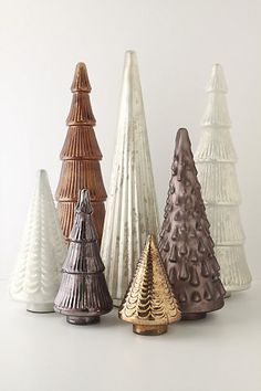 five different colored ceramic christmas trees on a white surface