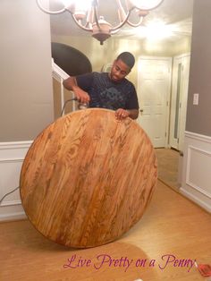 a man standing next to a large wooden object on top of a hard wood floor