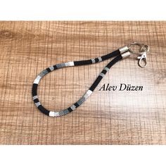 a black and white lanyard with silver metal clasps on a wooden table top