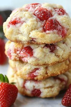 three strawberry shortbread cookies stacked on top of each other with strawberries in the background