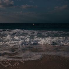 the waves are crashing on the beach at night