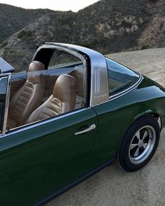 a green sports car parked on the side of a dirt road