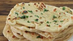 a stack of pita bread sitting on top of a white plate covered in cheese