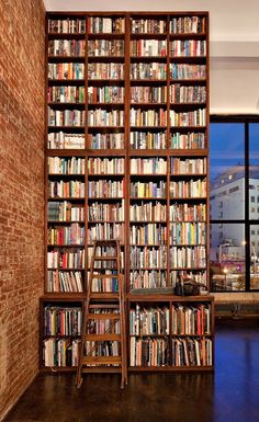 a large bookcase filled with lots of books in a living room next to a window