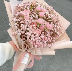 a person holding a bouquet of pink flowers