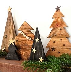 three wooden christmas trees sitting on top of a mantle