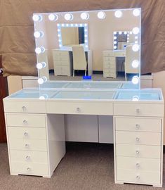 a white vanity with lighted mirror and drawers