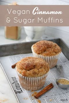 two cinnamon and sugar muffins sitting on top of a tray next to spices