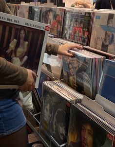 a person holding up a record player in front of a bunch of records on display