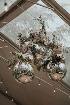 three disco ball vases filled with flowers hanging from the ceiling