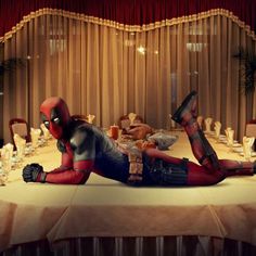 a woman dressed as deadpool laying on top of a table