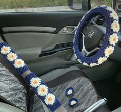 the steering wheel cover is decorated with daisies and crocheted in blue yarn